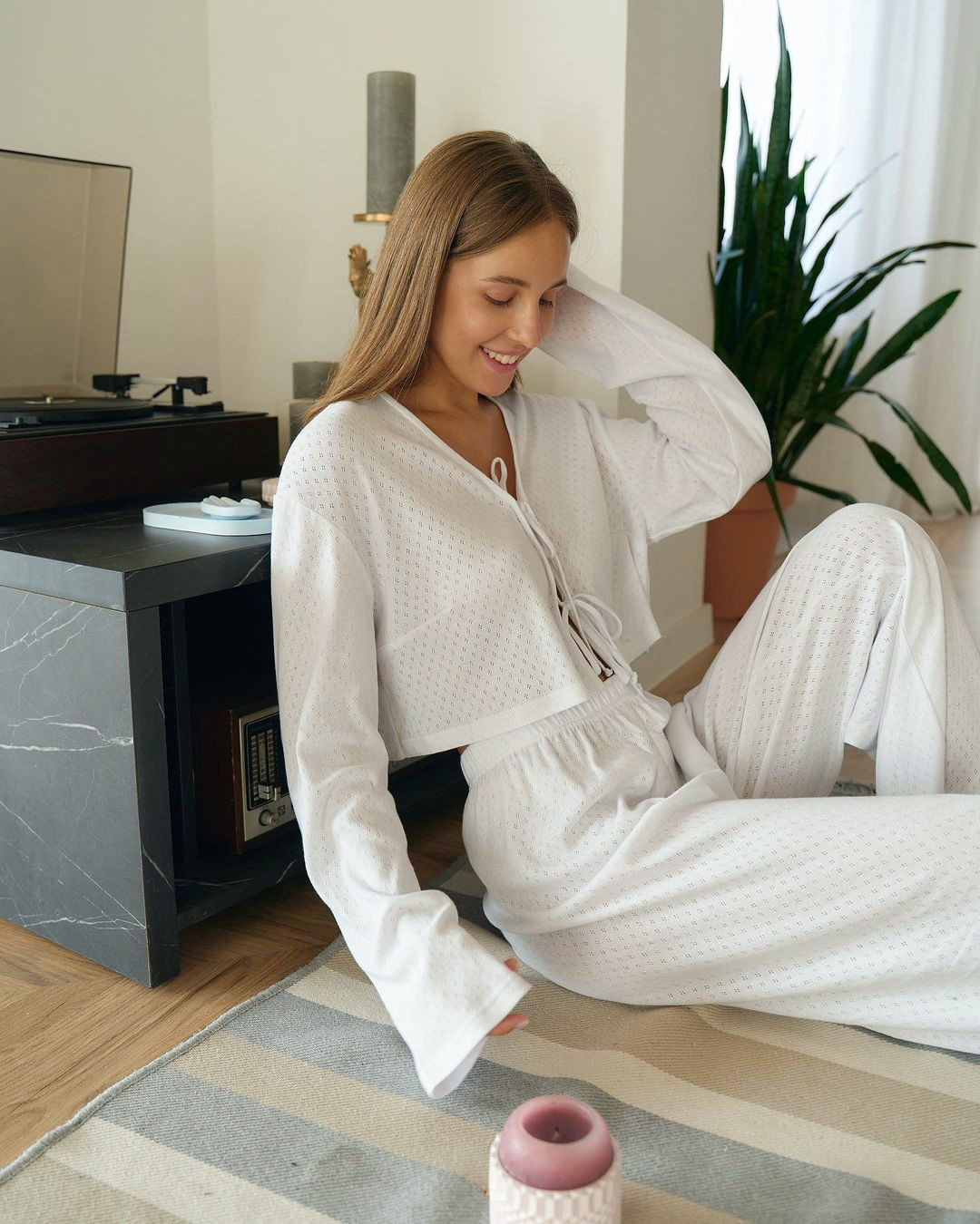 Woman in soft cream pajamas on a sunlit bed
